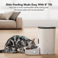 A cat eating from the automatic voice record feeder. A couch in the background.