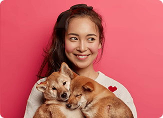 Happy woman holds two adorable Shiba Inu puppies