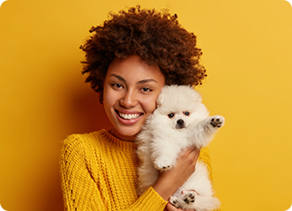 Cheerful woman cuddling white Pomeranian puppy